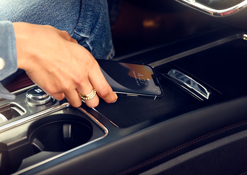 A hand is shown placing a smartphone on the available wireless charging pad. | Rydell Lincoln in Independence IA