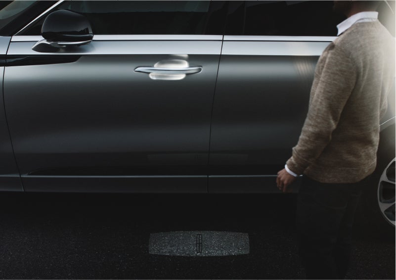 A person approaches a 2023 Lincoln Aviator® Grand Touring as the Lincoln Embrace sequence of welcome lighting illuminates | Rydell Lincoln in Independence IA