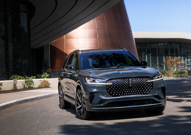 A gray 2025 Lincoln Aviator® SUV is parked outside a modern building with the sun shining. | Rydell Lincoln in Independence IA