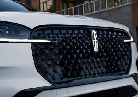 The black grille of a white 2025 Lincoln Aviator® SUV is shown with its fog lights on. | Rydell Lincoln in Independence IA