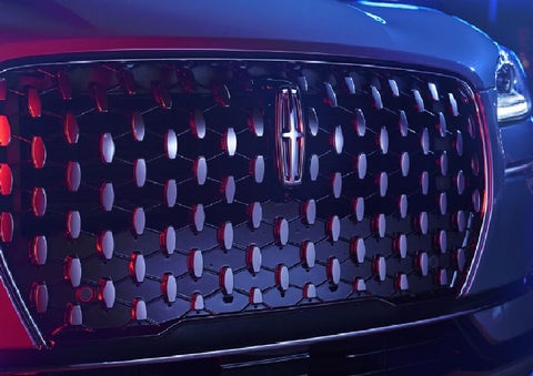The grille of a 2025 Lincoln Corsair® SUV reflects neon light at night. | Rydell Lincoln in Independence IA