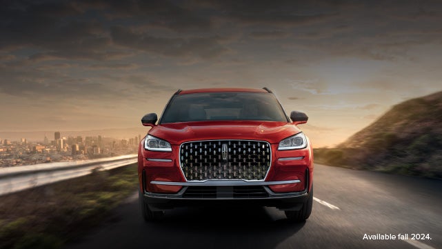 A 2025 red Lincoln Corsair® SUV is being driven down a road at sunset. | Rydell Lincoln in Independence IA