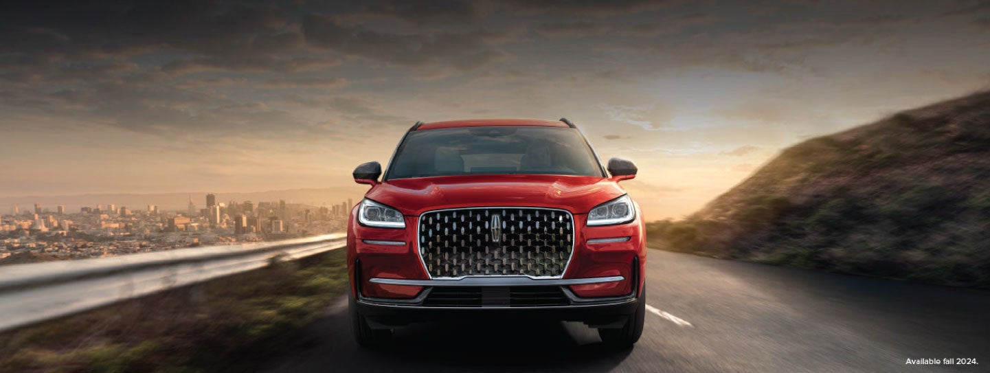 A 2025 red Lincoln Corsair® SUV is being driven down a road at sunset. | Rydell Lincoln in Independence IA