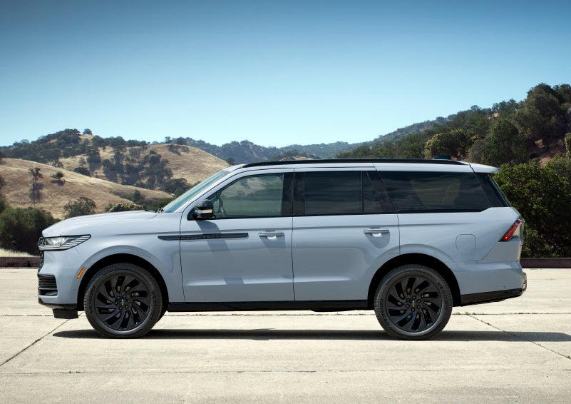 A valet is unloading luggage from the rear cargo area of a 2025 Lincoln Navigator® SUV.