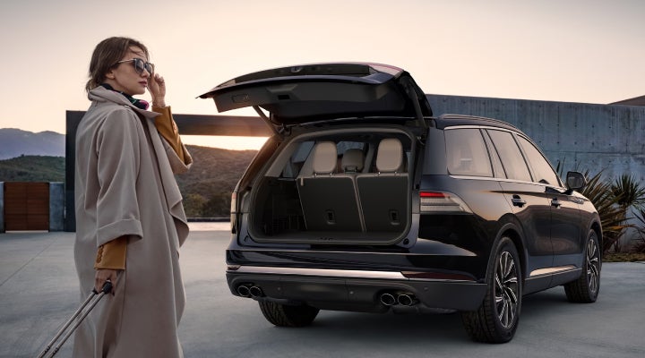 A woman approaches a 2026 Lincoln Aviator® SUV with its rear liftgate open. | Rydell Lincoln in Independence IA