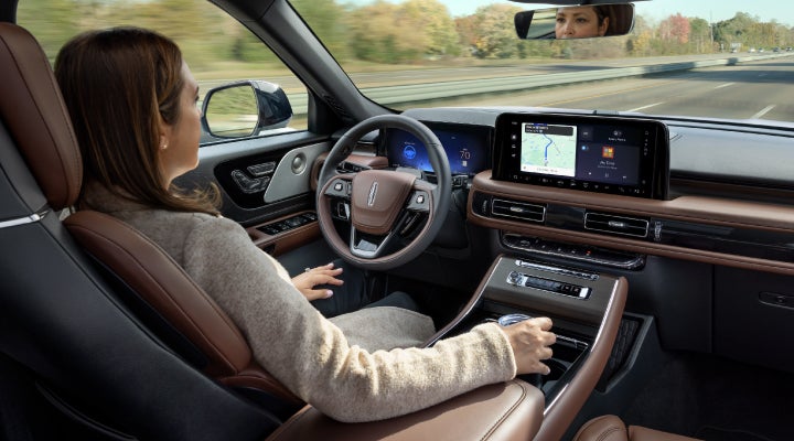 A 2026 Lincoln Aviator® SUV is being driven hands-free on a highway near a forest | Rydell Lincoln in Independence IA