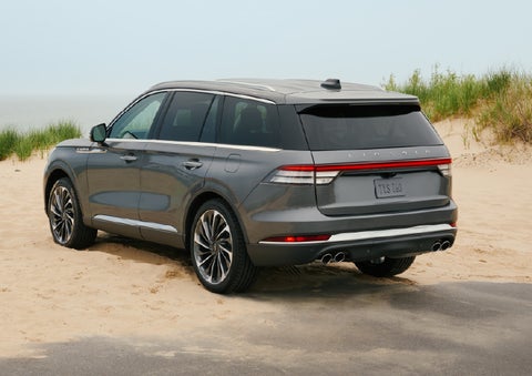 A 2027 Lincoln Aviator® SUV is parked next to sand dunes. | Rydell Lincoln in Independence IA