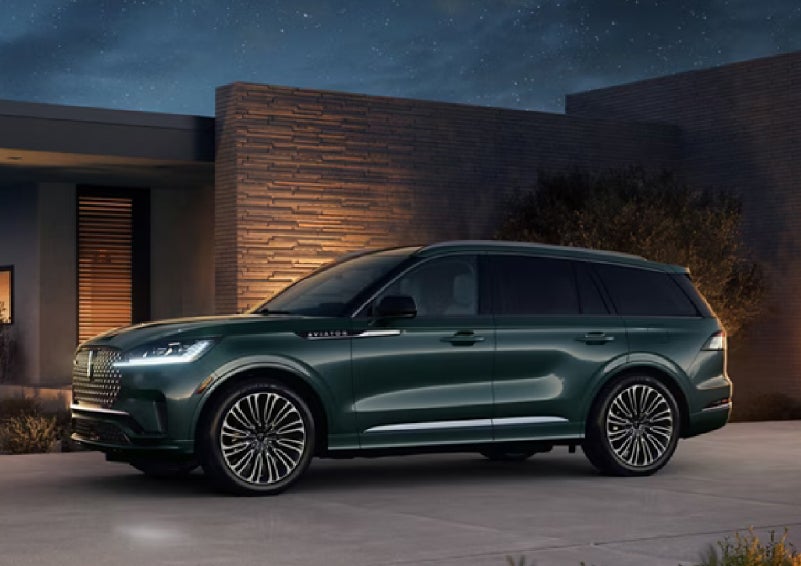 A green 2027 Lincoln Aviator® SUV is parked outside a contemporary home. | Rydell Lincoln in Independence IA