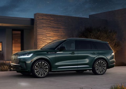 A green 2027 Lincoln Aviator® SUV is parked outside a contemporary home. | Rydell Lincoln in Independence IA