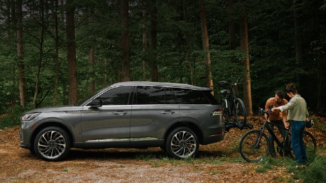 A father and son load e-bikes on a bike rack attached to a 2027 Lincoln Aviator® SUV. | Rydell Lincoln in Independence IA